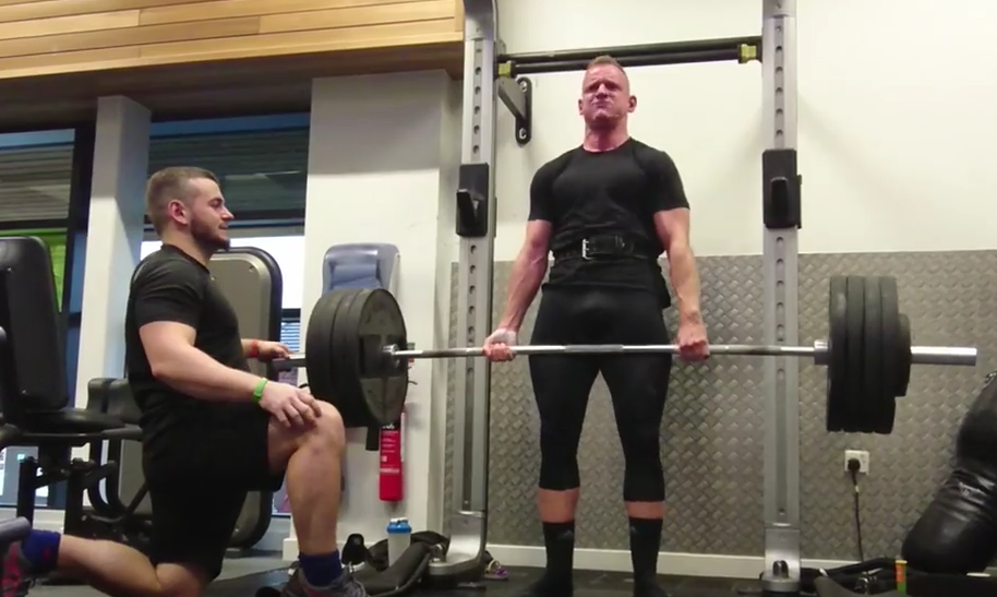 Coaching a man to deadlift in a gym
