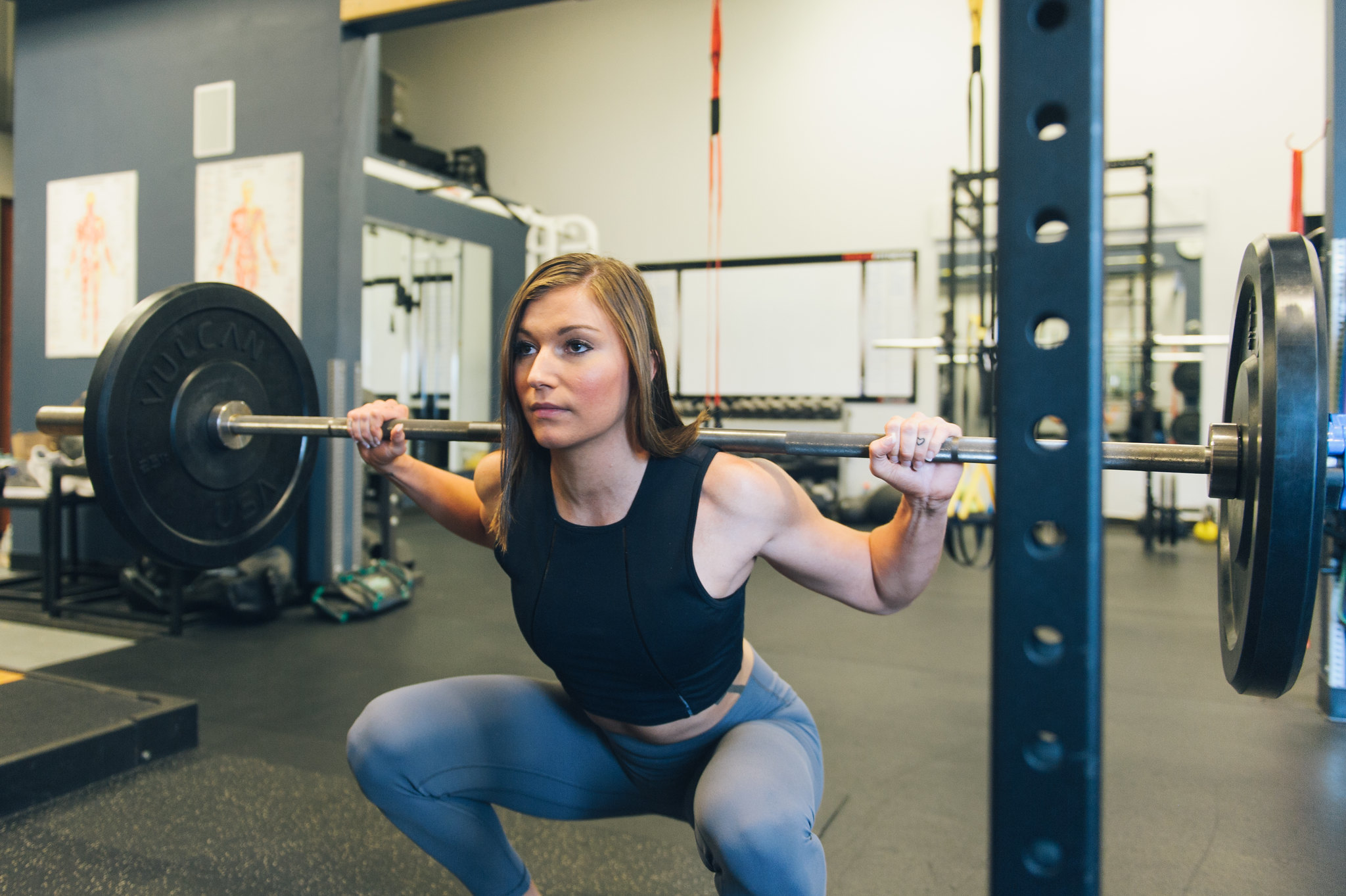 strength training women doing barbell back squat in gym